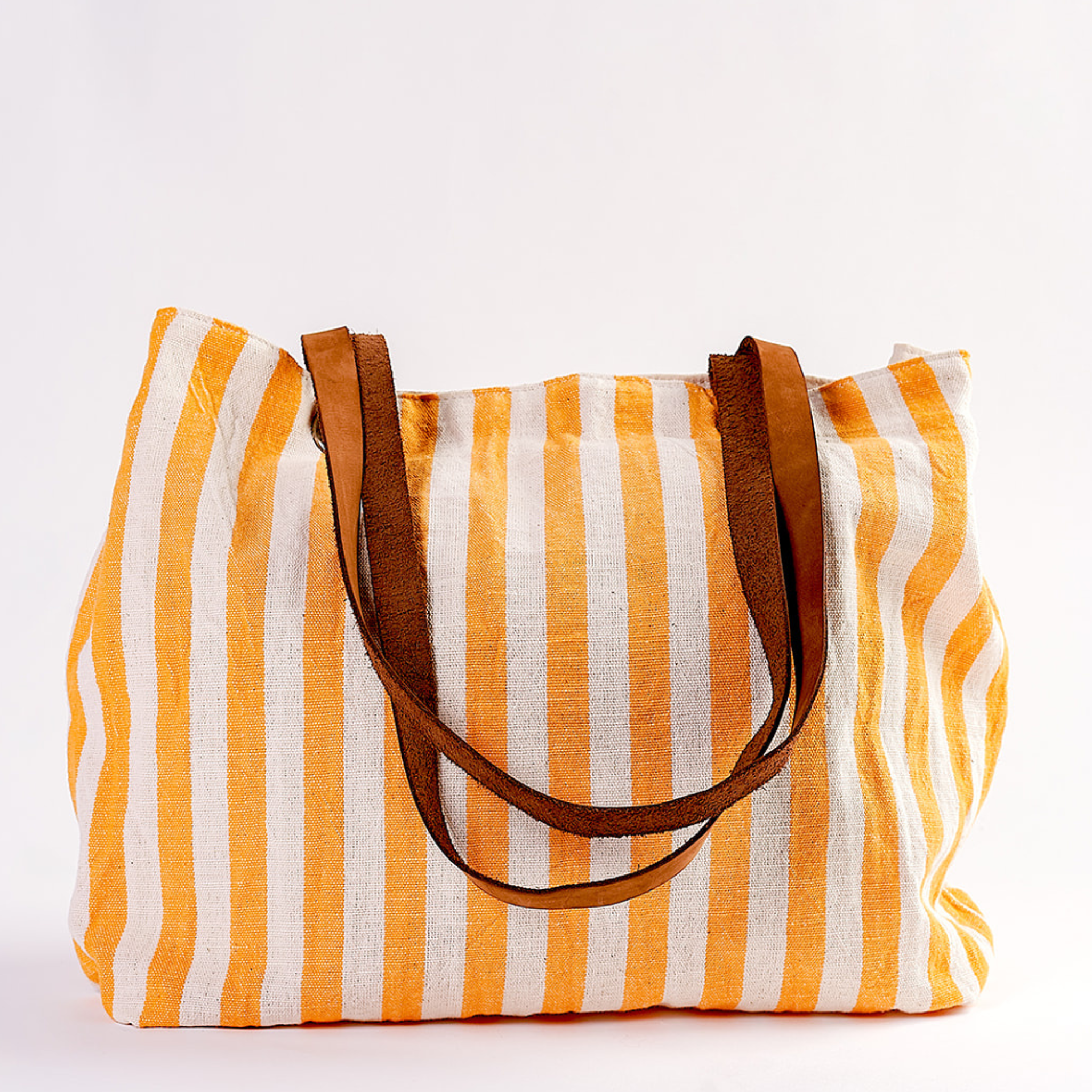 A striped canvas tote bag with vertical yellow and white stripes and brown shoulder straps, photographed against a plain white background.