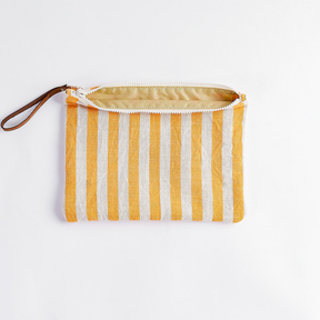 A striped fabric pouch with vertical yellow and white stripes, featuring a brown wrist strap and an open cream zipper, shown on a plain white background.
